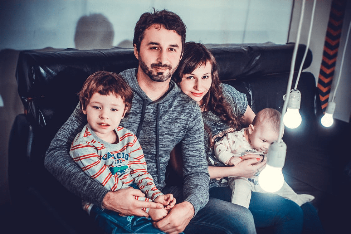 A man and two children sitting on the couch